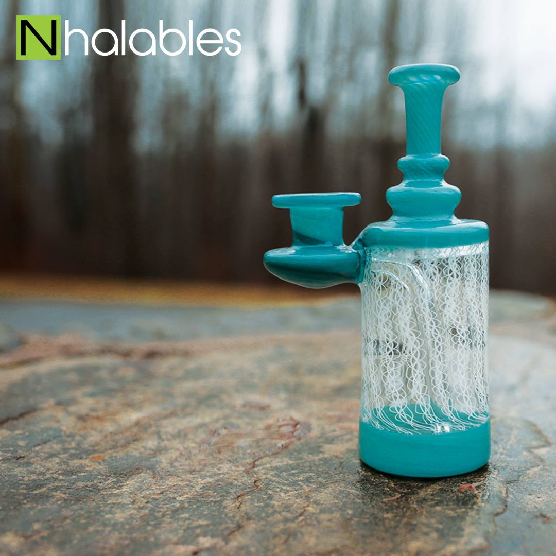 Nhalables Social Post showing a Jeff Heath Blue Zanfirico Bottle sitting on a rock in front of some trees.