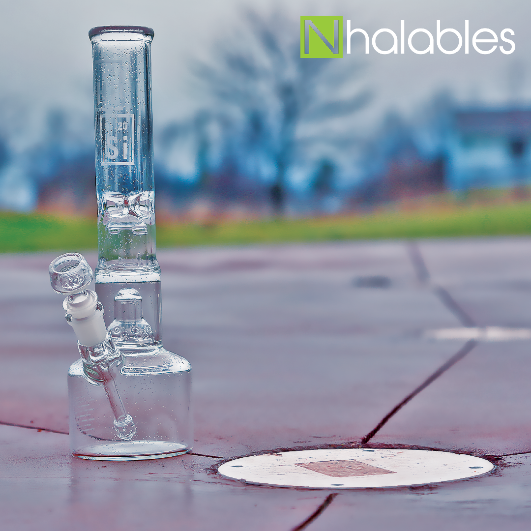 Nhalables Social Post Showing a HiSi Glass Double Bell Beaker sitting on a splash pad in the rain.